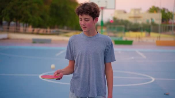 テニスラケットを持ち ピンポンボールを跳ねるティーンエイジャー スポーツ用品によるスローモーションフィルムクリップ — ストック動画
