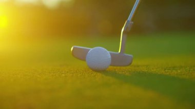 Yavaş çekimde golf sporu konsepti, golf sahasında golfçülerin golf sahasında kazanmak için deliğe vurması günbatımında güzel bir çim yoldur. Yeşil çimlere yakın şut atılıyor. Yazın rahatlamak için oynayan oyuncu için..