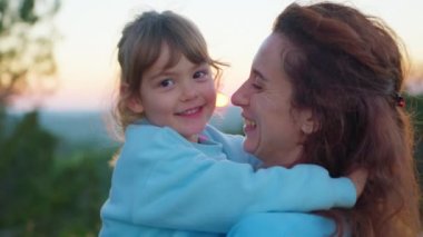 Sevecen, sevimli, evlat edinilmiş bir kız çocuğu koruyucu aileye sarılıyor gözleri kapalı bir anne, sevimli küçük bir kız çocuğu annesine sarılıyor şefkatli bir anın tadını çıkarıyor, manzarayı kapatıyor..