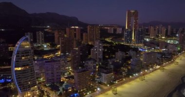 İspanya 'nın Benidorm kentindeki kıyı binalarının hava manzarası. Benidorm 'un güzel mavi saat hava manzarası. Huzurlu plajlar ve pürüzsüz Akdeniz 'de sokak lambaları uzakta parlıyor..