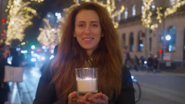 一个卷发的成年女子拿着蜡烛的画像 圣诞气氛 巴黎街头装饰着圣诞光彩夺目的装饰和背景灯 — 图库视频影像