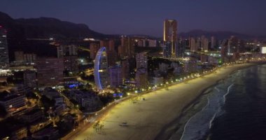 İspanya 'nın Benidorm kentindeki kıyı binalarının hava manzarası. Benidorm 'un güzel mavi saat hava manzarası. Huzurlu plajlar ve pürüzsüz Akdeniz 'de sokak lambaları uzakta parlıyor..