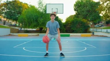 Ağır çekim sokak basketbolu. Basketbol antrenmanı yapan bir çocuk. Genç basketbol oynar. Sağlıklı yaşam tarzı ve hobi anlayışı. Basketbol topuna vuran tatlı bir çocuk..