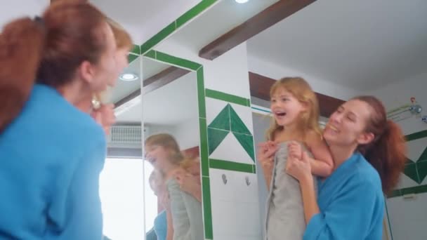 快乐的母亲和她美丽的小女儿在一起玩得很开心 在镜子前洗澡后 母亲和女儿在一起玩耍 一边看着镜子一边笑 — 图库视频影像