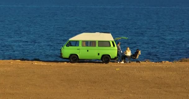 朋友们在蓝色的海面上享受一个轻松的夏夜 跟踪绿色野营车的无人驾驶飞机继续沿着海岸线飞行 在美国 空中看汽车在靠近海洋的悬崖上的家 — 图库视频影像