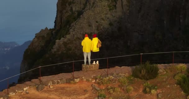 两名观光客背着背包慢行 在夕阳西下的阳光下勾勒出轮廓 相机跟随夫妇旅行或冒险 一家人在美丽的山谷里散步 — 图库视频影像
