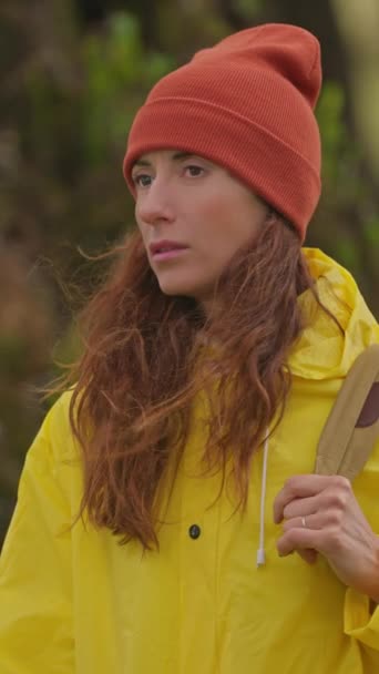 スローモーションカメラは バックパック付きの黄色いレインコートの女性ハイカーに続きます バックパックハイキングの魅力的な幸せな若い女の子 マデイラ島の山々の地平線に太陽を設定する — ストック動画