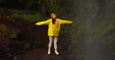 Sarı ceketli bir şelale gezisi. Yürüyüş, şelaleye seyahat tatilde ya da seyahatte. Kaygısız, özgür, kadın yürüyüşçü eğleniyor ve macerada yalnız kalmaktan zevk alıyor.