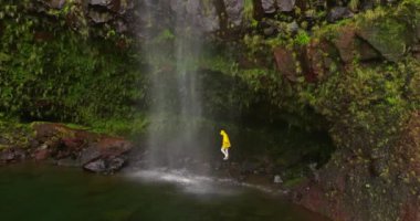Sarı ceketli bir şelale gezisi. Yürüyüş, şelaleye seyahat tatilde ya da seyahatte. Kaygısız, özgür, kadın yürüyüşçü eğleniyor ve macerada yalnız kalmaktan zevk alıyor.