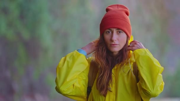 在高地瀑布附近穿着黄色雨衣的女旅行者 享受着大自然和生活 在山上旅行 在旅途中冒险 生活方式的概念 穿着黄色围裙的旅客 — 图库视频影像