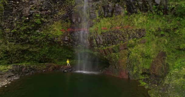 女性の空中ビューは滝の下に腕を開き 屋外の休暇で探検する自然の冒険をハイキングします — ストック動画