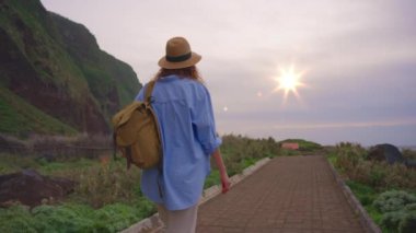 Kamera kadın yürüyüşçüyü sırt çantasıyla takip ediyor. Gezgin yürüyüşçü, doğa ve hayatın tadını çıkarıyor. Dağlarda seyahat, yolculukta macera. Yaşam tarzı konsepti. Madeira 'da dağ yolunda yürüyen bir kadın..