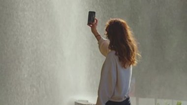 Blog doğa şelalesi arka planı için fotoğraf çeken kadın.