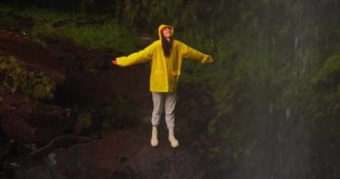 Şelale altında kollarını açmış, doğa macerasında yürüyüş yapan bir kadının hava manzarası. Seyahat, özgürlük ya da yolculuk.