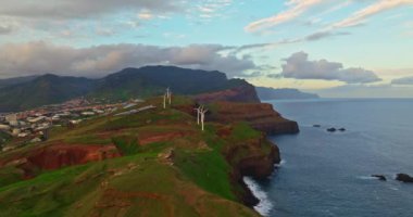 Şafak vakti okyanusun üzerindeki bir tepenin üzerinde duran yel değirmenlerinin havadan görünüşü Canical, Madeira, Portekiz.