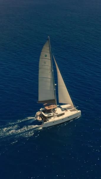 インド洋上空でドローン飛行 空中映像 白い目覚めのある深い青い海を航行する豪華な帆船のリアビュー カメラは青い海水のカタマランに従います — ストック動画