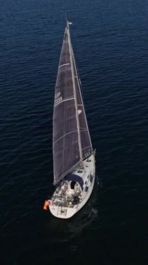 Batan güneşin ışınlarında yelkenli beyaz bir yatın hava görüntüsünü ayarlıyorum. Suyun üstünde parla. Mavi denizde yüzen bir yatın silueti. İHA 'dan ateşlenmiş..