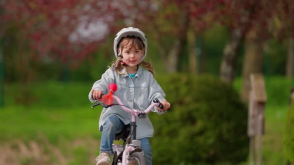 Niña Linda Casco Protección Monta Una Bicicleta Con Ruedas Auxiliares — Vídeos de Stock