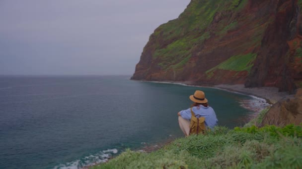 모자에 바위에 바다의 전망을 즐기는 여행자 — 비디오