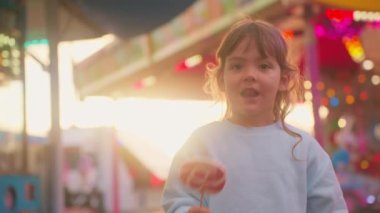 Şekerli mutlu küçük kız, eğlence parkında ışıklarla eğleniyor..