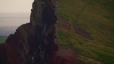 Mavi Atlantik Okyanusu 'nun yanındaki kayalık sahil şeridi. Yeşil bir adanın kıyısında. Dağları ve okyanus kayalıkları olan Madeira manzarası. Madeira Adası 'nın engebeli kıyı şeridine nefes kesici bir manzara..
