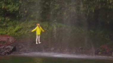 Şelale altında kollarını açmış, doğa macerasında yürüyüş yapan bir kadın açık hava tatilinde keşfe çıkıyor. Seyahat, özgürlük ya da yolculuk.