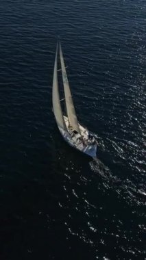 Batan güneşin ışınlarında yelkenli beyaz bir yatın hava görüntüsünü ayarlıyorum. Suyun üstünde parla. Mavi denizde yüzen bir yatın silueti. İHA 'dan ateşlenmiş..