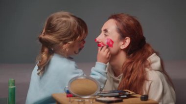 Tatlı kız annesi için makyaj yapıyor. Yüz boyama. Birlikte mutlu anlar. Anne ve kızı..