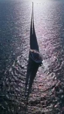 Açık okyanus derin mavi denizinde yüzen bir yatın insansız hava aracı videosu. Açık denizde yelkenli yatlı güneş deniz manzarası. Okyanus körfezinde yelkenlilerle açılmak. Güneşli yaz gününde lüks yat hayatı..