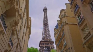 View of the Eiffel Tower from one of the famous streets of Paris. Parisian architecture of houses in the center of the capital. High quality 4k footage