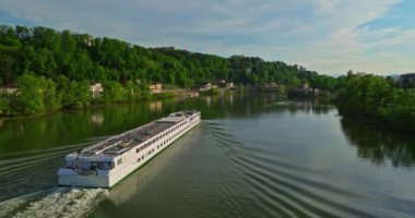 Gün batımında mavi bir nehir boyunca havadan izleniyor. Bir turist gemisi nehir boyunca ilerliyor. Lyon, Fransa.