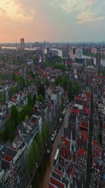 Amsterdam, Hollanda şehri. Şehir merkezinde elektrikli tekneleri olan kanalların havadan görüntüsü. İnsansız hava aracı Amsterdam bahar manzarası dar eski evler, kanallar. Eski merkez hava görüntüsü oluşturuluyor.