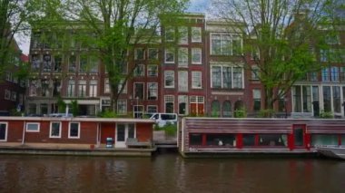 Amsterdam manzaralı kanal manzaralı, turist teknesiyle, kanal boyunca eski evlerle çekimler yapılıyor. Bisiklet ve elektrik taşımacılığı.