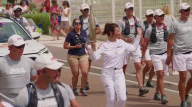 Migennes, Fransa, 11 Temmuz 2024: Paris Olimpiyatları için Yonne 'dan geçen Olimpiyat Ateşi. Fransa 'da, korumalar ve sokak kalabalığıyla çevrili olimpiyat meşalesi. Olimpiyat meşale geçit töreni..