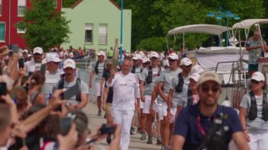 Migennes, Fransa, 11 Temmuz 2024: Paris Olimpiyatları için Yonne 'dan geçen Olimpiyat Ateşi. Fransa 'da, korumalar ve sokak kalabalığıyla çevrili olimpiyat meşalesi. Olimpiyat meşale geçit töreni..