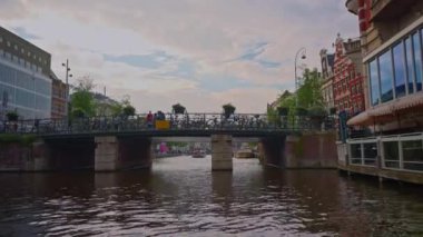 Hollanda, Amsterdam, 24 Haziran 2024: Geleneksel evler, kanallar, bisikletler, kentsel ulaşım. Avrupa 'da bir şehrin turizm merkezi. Şehirde dolaşan ve gezen bir sürü insan..