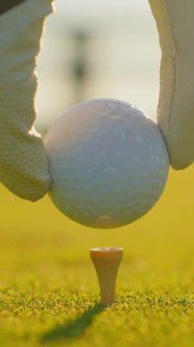 Çok yönlü bir video. Golf eldiveni giymiş bir erkek topu sahaya sürüyor. Golfçü golf sahasındaki golf sahasına golf topu koyuyor. Kapat..