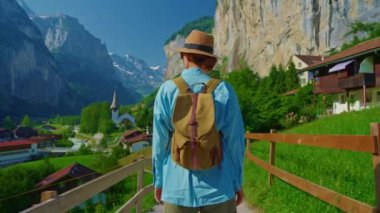 Lauterbrunnen, İsviçre. Sırt çantalı genç bir turist, Alp dağlarında şelalesi olan ünlü bir İsviçre köyünün inanılmaz manzarası boyunca yürüyor..