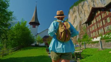Lauterbrunnen, İsviçre. Sırt çantalı genç bir turist, Alp dağlarında şelalesi olan ünlü bir İsviçre köyünün inanılmaz manzarası boyunca yürüyor..