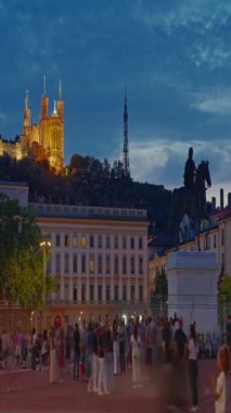 Dikey video. Bellecour Meydanı 'nda gün batımında Lyon şehir merkezindeki ana yer olan Kral 14. Louis, Lyon, Fransa' nın heykeliyle. Zaman Uygulaması.