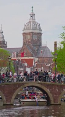 Hollanda, Amsterdam, 30 Temmuz 2024: Şehirde gezen ve gezen bir grup insan. Geleneksel evler, kanallar, bisikletler, şehir ulaşımı. Avrupa 'da bir kentin turizm merkezi.