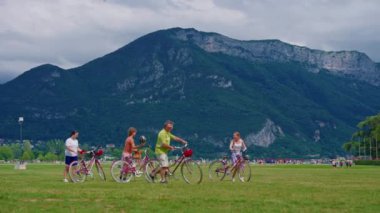 Annecy, Fransa, 31 Temmuz 2024: Annecy kasabasının arka planında dağları olan ve insanların yeşil çimlerin üzerinde dinlendiği toprak seti.