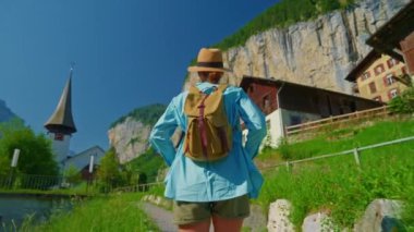 Lauterbrunnen, İsviçre. Sırt çantalı genç bir turist, Alp dağlarında şelalesi olan ünlü bir İsviçre köyünün inanılmaz manzarası boyunca yürüyor..