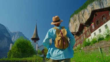 Lauterbrunnen, İsviçre. Sırt çantalı genç bir turist, Alp dağlarında şelalesi olan ünlü bir İsviçre köyünün inanılmaz manzarası boyunca yürüyor..