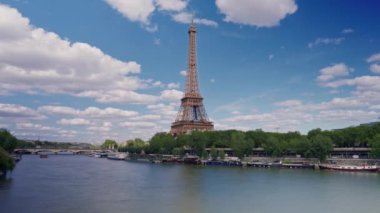 Seine nehri boyunca Eyfel Kulesi 'nin zaman çizelgesi. Uçan tekneler hareket bulanıklığıyla geçiyor. Güneşli ama bulutlu bir bahar günü Paris Şehri nehir kenarı manzaralı köprünün tarihi geçmiş panorama.