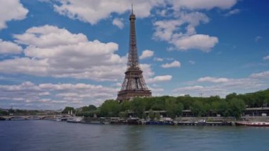 Seine nehri boyunca Eyfel Kulesi 'nin zaman çizelgesi. Uçan tekneler hareket bulanıklığıyla geçiyor. Güneşli ama bulutlu bir bahar günü Paris Şehri nehir kenarı manzaralı köprünün tarihi geçmiş panorama.