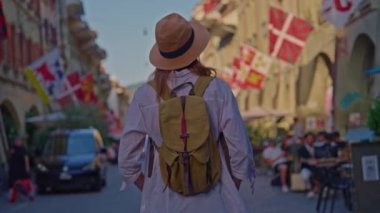 Şık şapkalı çekici bir kız tatilini yalnız geçirir, Alp çayırlarında seyahat eder. Sırt çantalı bir turist inanılmaz manzarayla İsviçre 'yi geziyor..