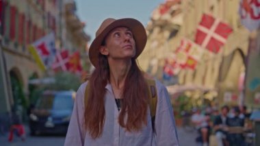 İsviçre 'nin merkezinde İsviçre bayrağının arka planında dikilen şapkalı bir kadın şehre bakıyor. Yüksek kalite 4k görüntü