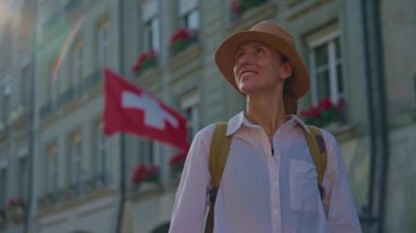İsviçre 'nin merkezinde İsviçre bayrağının arka planında dikilen şapkalı bir kadın şehre bakıyor. Yüksek kalite 4k görüntü
