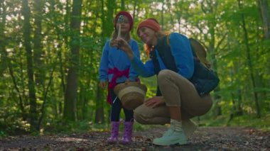 Bir anne ve sevimli küçük kızı ormanda büyük bir mantar buldular ve birlikte bakıyorlar, tatilde boş zamanlarının tadını çıkarıyorlar. Çocuk mutlu..